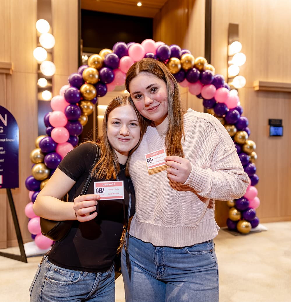Two GEM mentees smile and display their name badges at a Girls E-Mentorship GEMinar